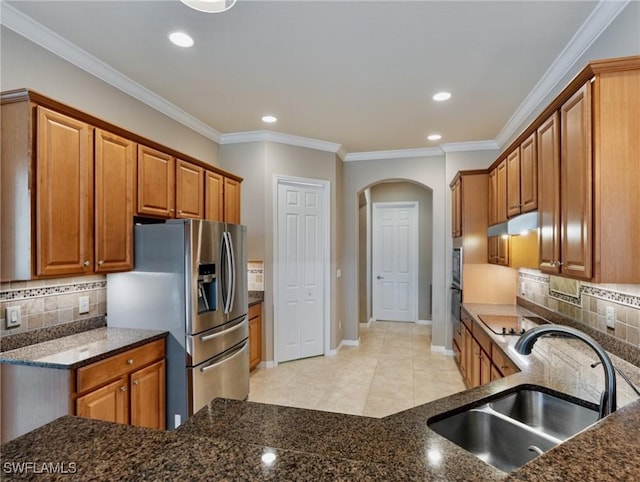 kitchen with sink, backsplash, stainless steel appliances, and dark stone countertops