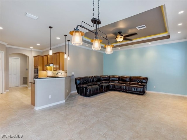 living room with ceiling fan, ornamental molding, and a raised ceiling