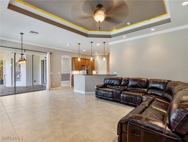 living room featuring light tile patterned floors, ceiling fan, ornamental molding, and a raised ceiling