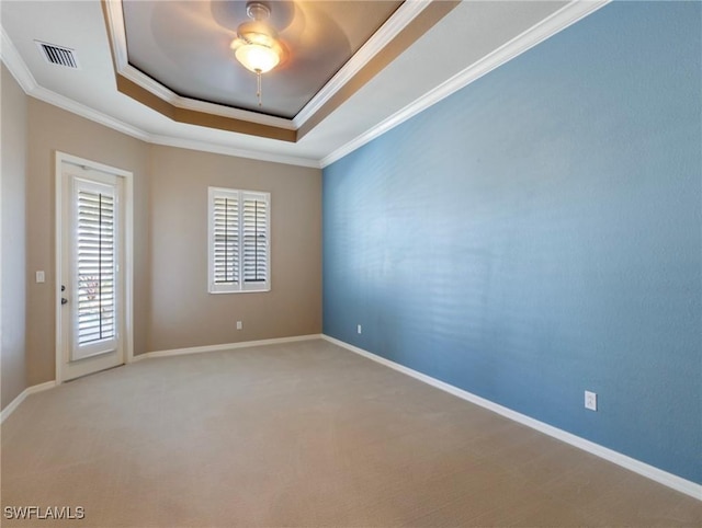 carpeted spare room with ceiling fan, ornamental molding, and a raised ceiling