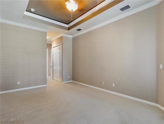 carpeted spare room with crown molding and a raised ceiling