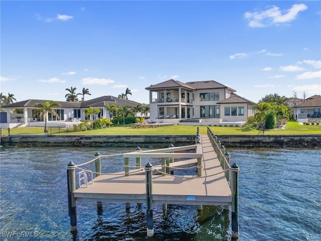 dock area with a water view, a yard, and a balcony