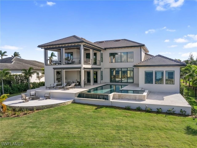 back of house with a patio, a balcony, a lawn, and a pool with hot tub