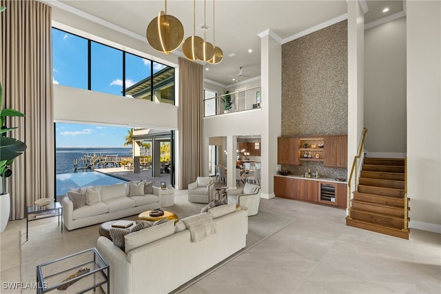 living room with a towering ceiling, a water view, french doors, and ornamental molding