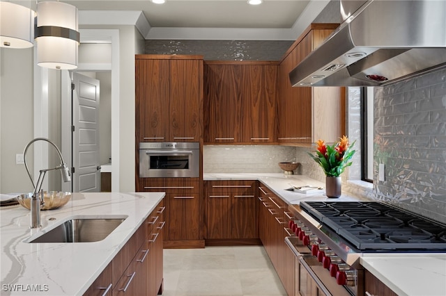 kitchen featuring light stone counters, sink, wall chimney range hood, stovetop, and oven