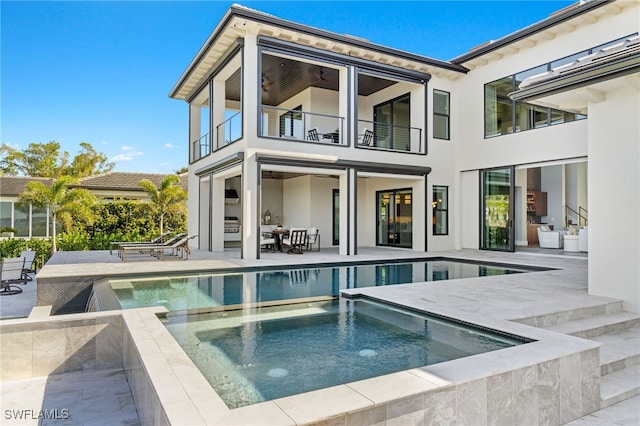 back of property featuring a patio area, a balcony, and a pool with hot tub