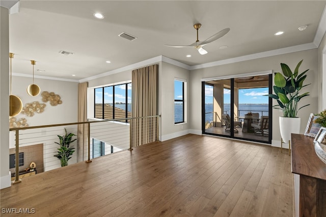 living room featuring hardwood / wood-style floors, ceiling fan, a water view, and crown molding