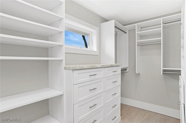 walk in closet with light hardwood / wood-style floors