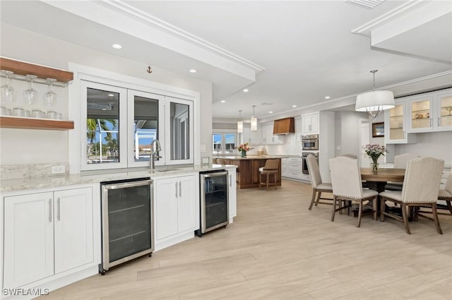 kitchen with wine cooler, light stone counters, and white cabinets