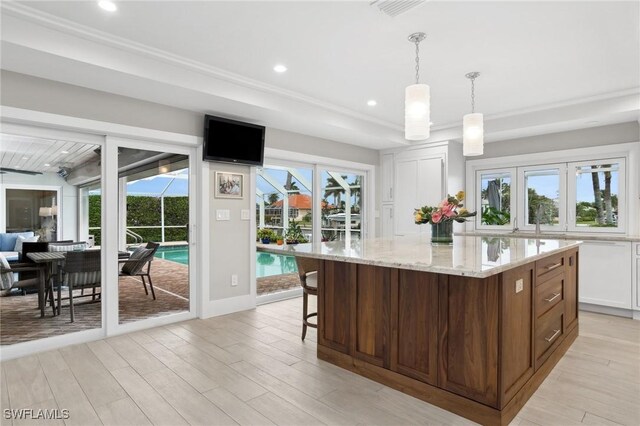 kitchen featuring white cabinets, a center island, decorative light fixtures, and a healthy amount of sunlight