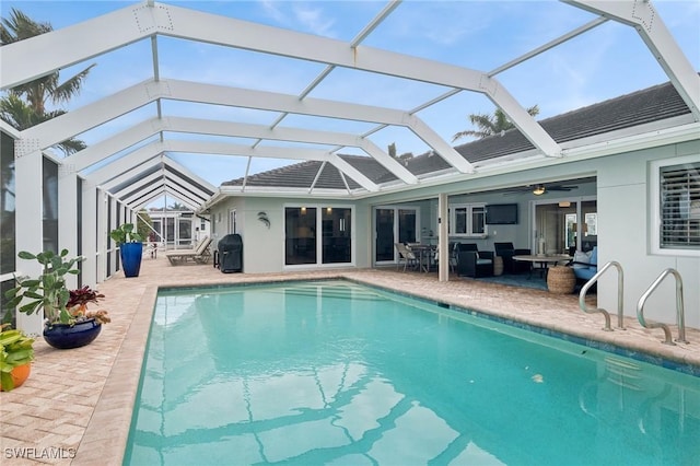 view of swimming pool with a patio area, ceiling fan, and glass enclosure