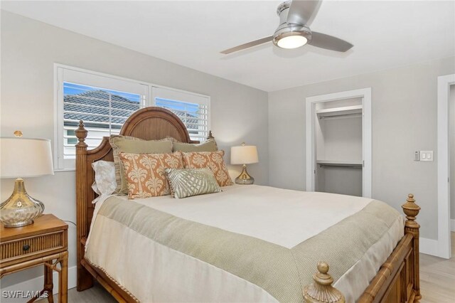 bedroom with ceiling fan, a spacious closet, light hardwood / wood-style flooring, and a closet