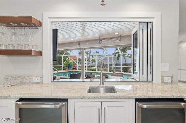 kitchen featuring white cabinetry, sink, light stone countertops, and dishwasher