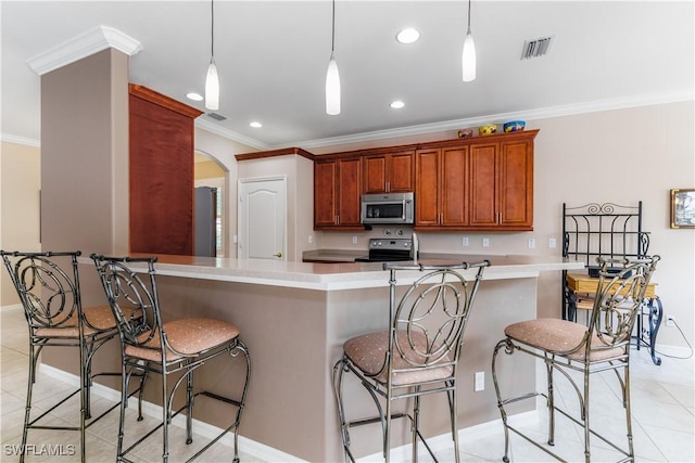 kitchen featuring decorative light fixtures, ornamental molding, stainless steel appliances, and a breakfast bar