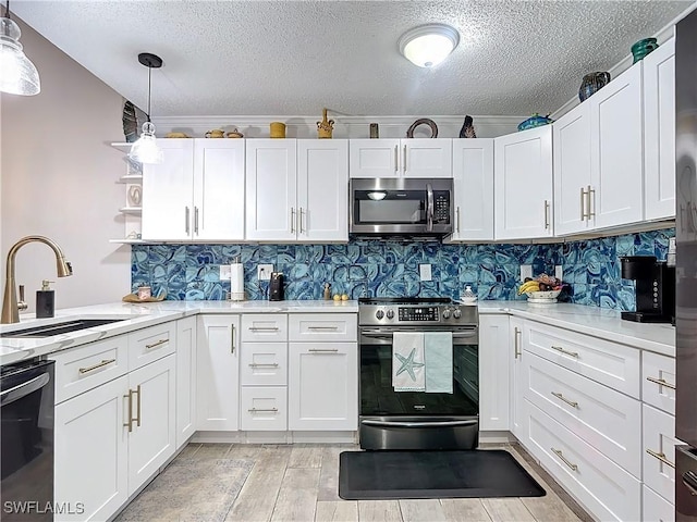 kitchen with white cabinets, appliances with stainless steel finishes, decorative light fixtures, and sink