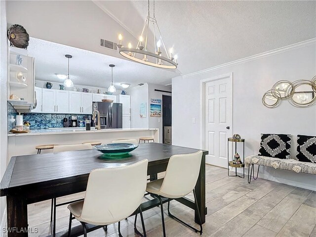 dining area featuring ornamental molding, a textured ceiling, lofted ceiling, and a notable chandelier