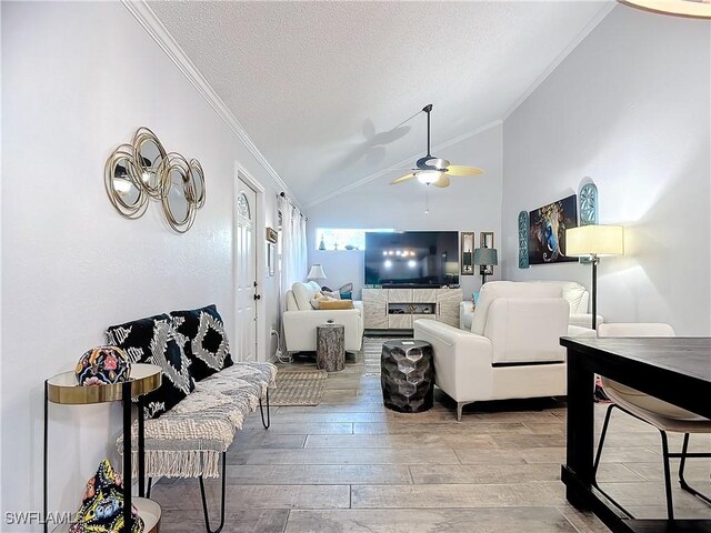 living room with ceiling fan, wood-type flooring, a textured ceiling, lofted ceiling, and ornamental molding