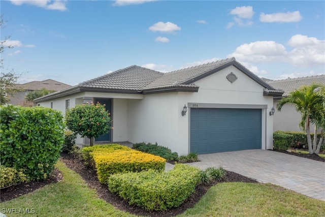 ranch-style home featuring a garage, a tiled roof, decorative driveway, and stucco siding