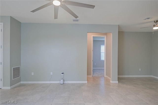 empty room featuring ceiling fan, visible vents, and baseboards