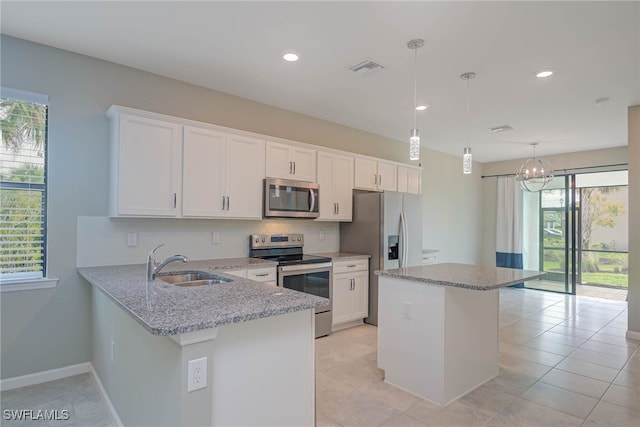 kitchen featuring sink, decorative light fixtures, light stone counters, kitchen peninsula, and stainless steel appliances