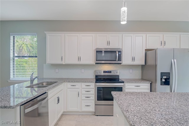 kitchen with appliances with stainless steel finishes, decorative light fixtures, white cabinetry, and sink