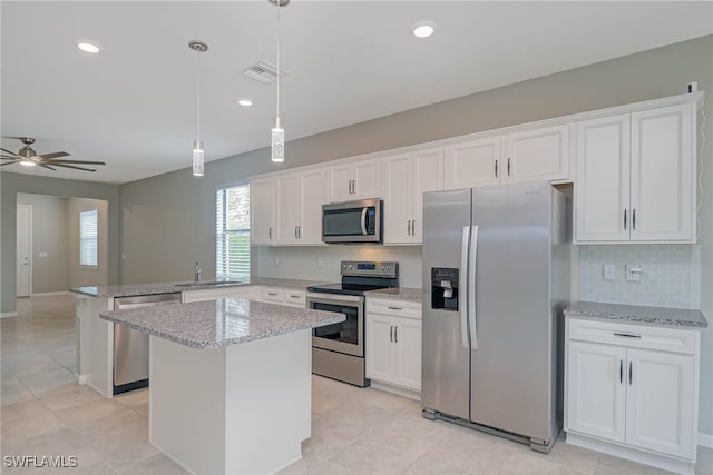 kitchen featuring stainless steel appliances, a kitchen island, ceiling fan, and white cabinetry