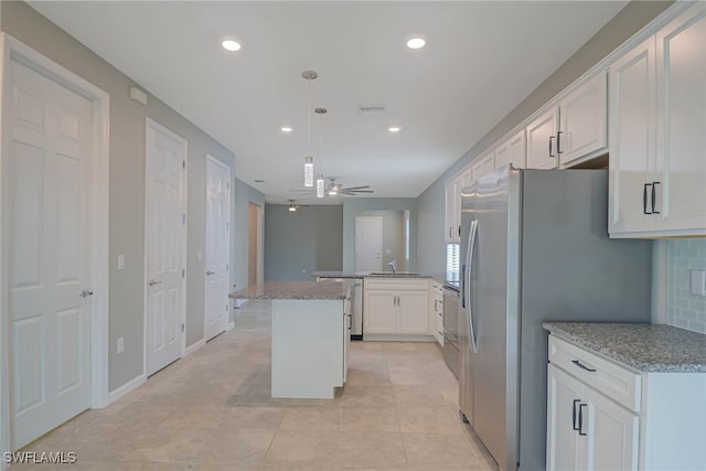 kitchen featuring pendant lighting, ceiling fan, decorative backsplash, a kitchen island, and white cabinetry