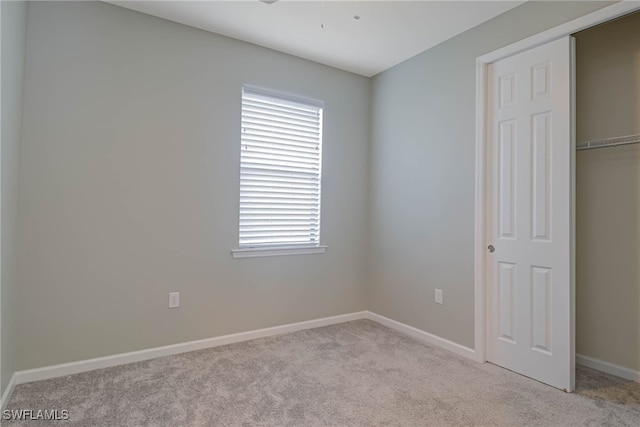 unfurnished bedroom with light carpet and a closet