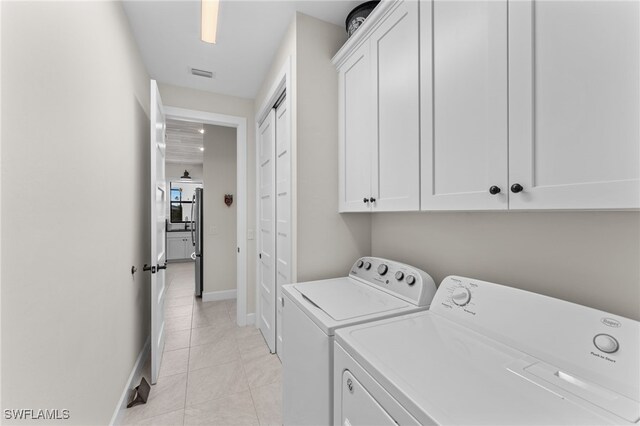 clothes washing area featuring cabinets, independent washer and dryer, and light tile patterned floors