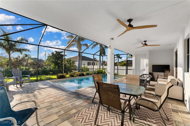 view of swimming pool featuring glass enclosure, ceiling fan, and a patio area