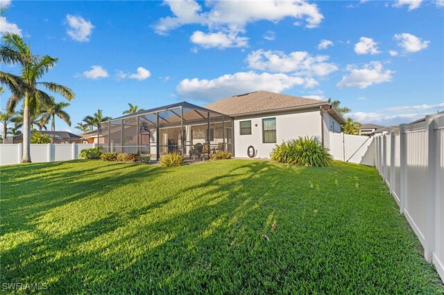 rear view of property featuring a lanai and a yard