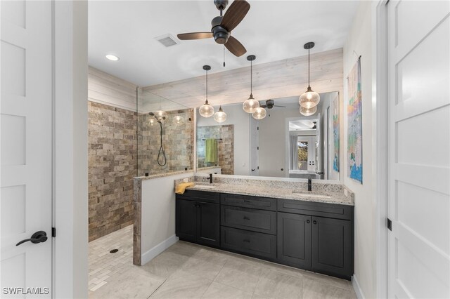 bathroom featuring tile patterned flooring, ceiling fan, a tile shower, and vanity