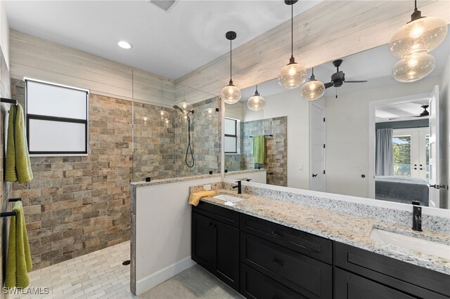 bathroom with tile patterned flooring, ceiling fan, a tile shower, and vanity