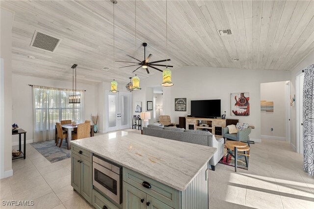 kitchen with hanging light fixtures, a center island, vaulted ceiling, and stainless steel microwave