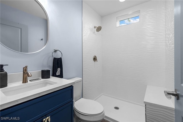 bathroom with tiled shower, vanity, and toilet