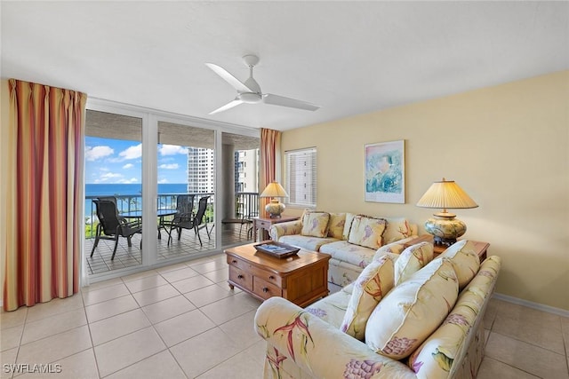 living room with ceiling fan, expansive windows, a water view, and light tile patterned floors