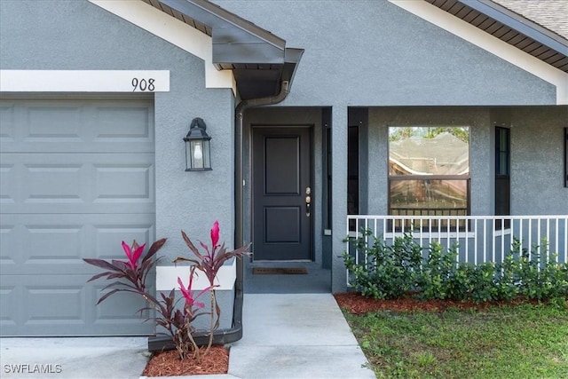 view of exterior entry with covered porch and a garage