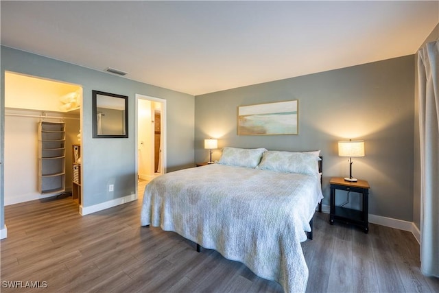 bedroom with dark hardwood / wood-style flooring, a spacious closet, a closet, and connected bathroom