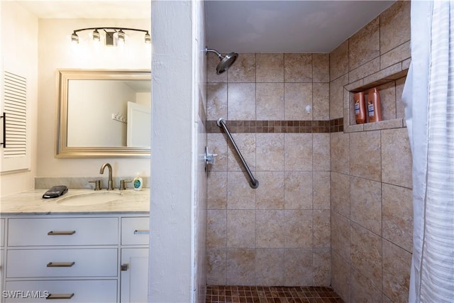 bathroom featuring tiled shower and vanity