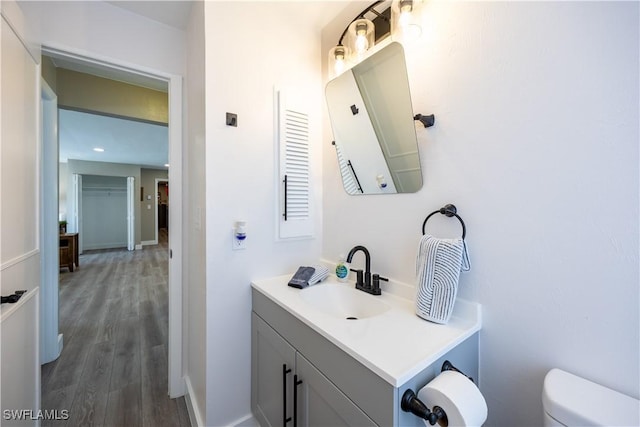 bathroom with hardwood / wood-style flooring, vanity, and toilet