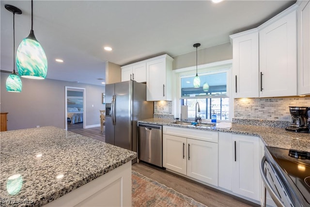 kitchen featuring decorative light fixtures, sink, white cabinetry, and stainless steel appliances