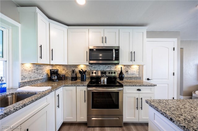 kitchen with tasteful backsplash, stainless steel appliances, hardwood / wood-style flooring, stone countertops, and white cabinets