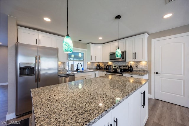 kitchen with decorative light fixtures, a kitchen island, sink, and appliances with stainless steel finishes