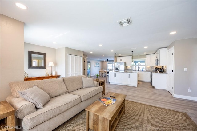 living room featuring ceiling fan, light wood-type flooring, and sink