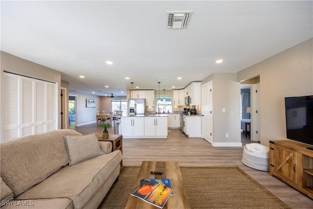 living room with ceiling fan and light wood-type flooring