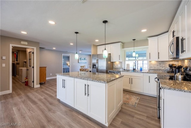 kitchen with pendant lighting, a center island, white cabinetry, and appliances with stainless steel finishes