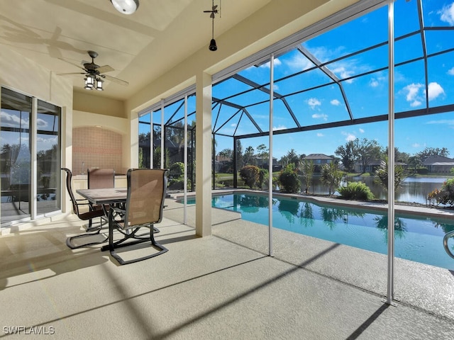 view of pool with a patio, a water view, glass enclosure, and ceiling fan