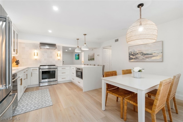 kitchen with white cabinets, decorative light fixtures, stainless steel appliances, and decorative backsplash