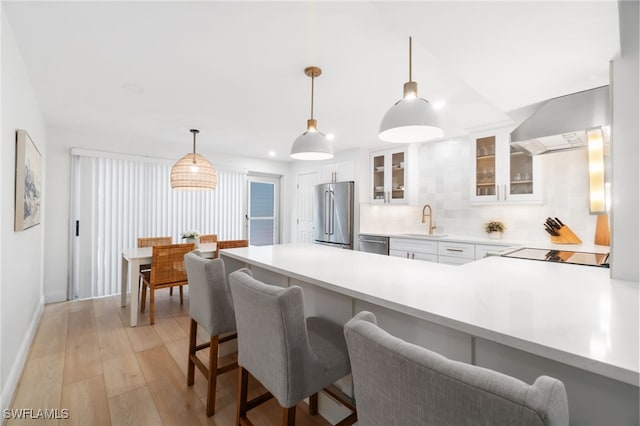 kitchen featuring appliances with stainless steel finishes, backsplash, exhaust hood, pendant lighting, and white cabinets