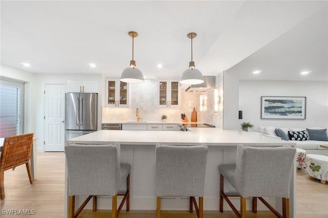 kitchen featuring a kitchen breakfast bar, kitchen peninsula, decorative light fixtures, high end fridge, and white cabinets